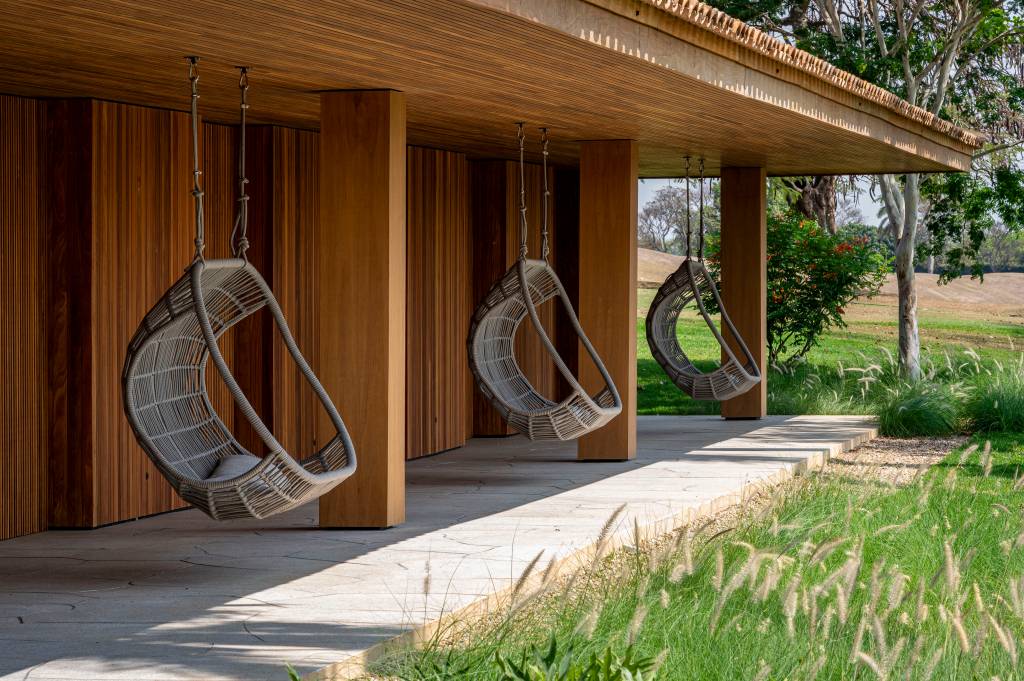 Casa de campo tem piscina semiolímpica e oito suítes elegantes. Projeto de Studio DWG. Na foto, varanda coberta, cadeira de balanço.