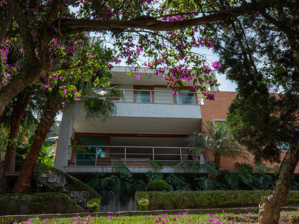 Casa em Teresópolis tem esquadrias, tijolinhos e cimento queimado na fachada. Projeto de Viviane Cunha.