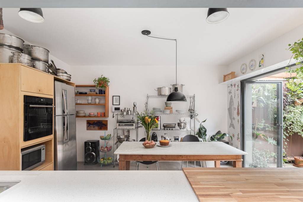 Casa tem cozinha com azulejos florais e edícula com banheiro canadense. Projeto de Pro.a Arquitetura.