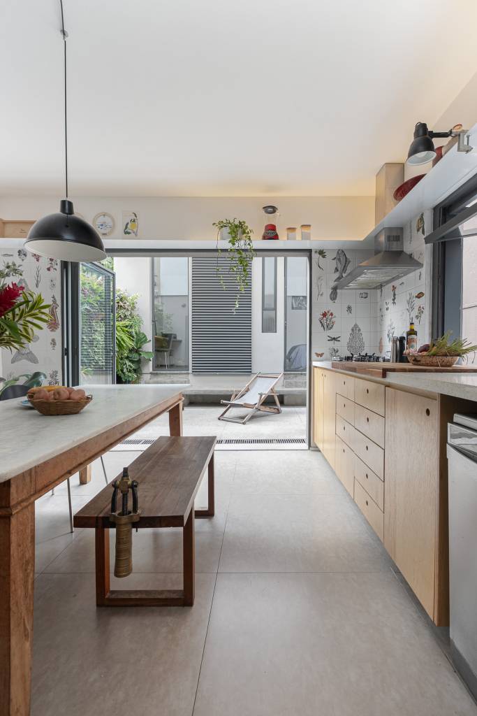 Casa tem cozinha com azulejos florais e edícula com banheiro canadense. Projeto de Pro.a Arquitetura.