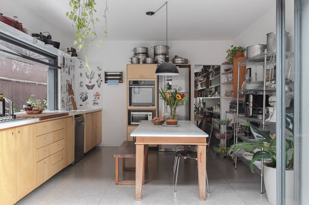 Casa tem cozinha com azulejos florais e edícula com banheiro canadense. Projeto de Pro.a Arquitetura.