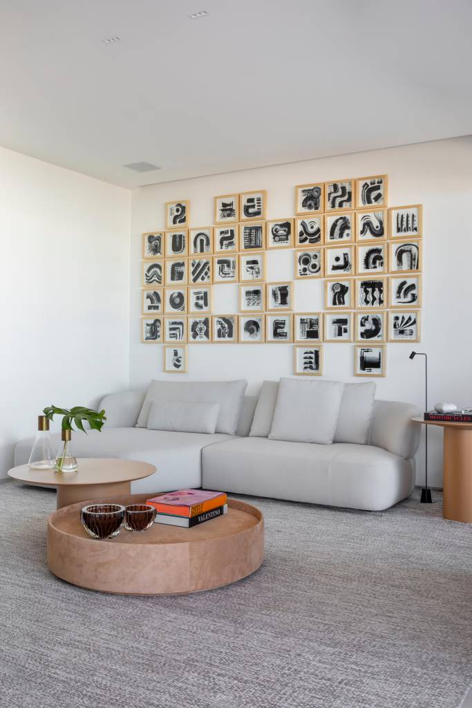Cobertura elegante tem piso de porcelanato e escada com degraus em Dekton. Projeto BF+Arquitetos. Na foto, sala de estar, composição de quadros pequenos na parede.