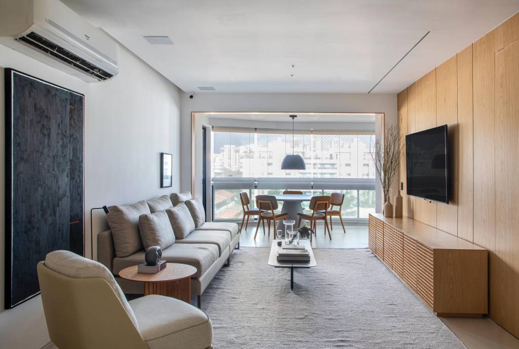 Cobertura elegante tem piso de porcelanato e escada com degraus em Dekton. Projeto BF+Arquitetos. Na foto, sala de estar neutra, tons bege.