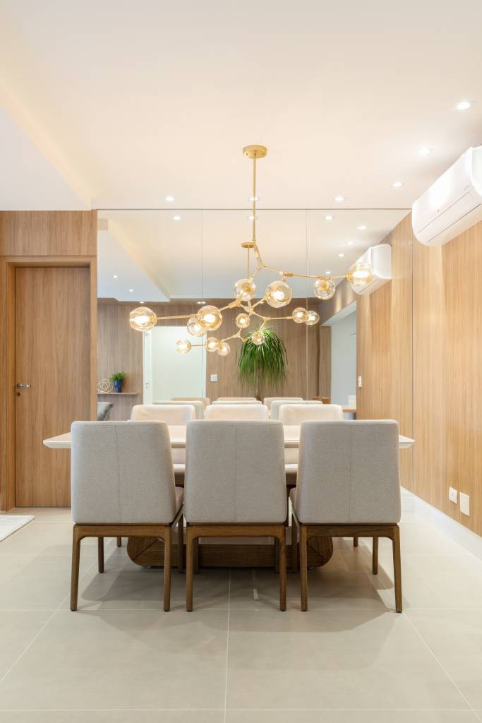 Mesa de granito verde é integrada à bancada de varanda gourmet neste apê. Projeto de RMV Interiores. Na foto, sala de jantar, luminária, espelho.