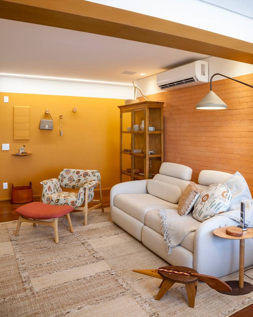 Paleta de cores vibrantes e brasilidade dão cara de casa à apê de 98 m². Projeto de Patrícia Viegas. Na foto, sala, sofá branco, poltrona estampada, parede amarela.