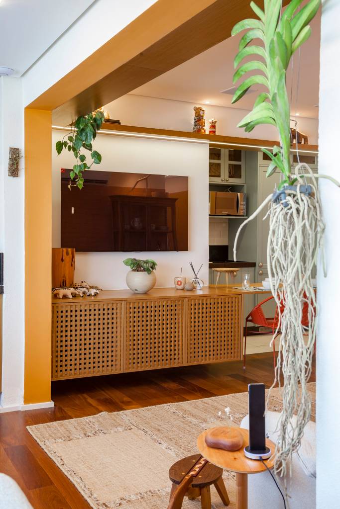 Paleta de cores vibrantes e brasilidade dão cara de casa à apê de 98 m². Projeto de Patrícia Viegas. Na foto, buffet, tv, planta suspensa.