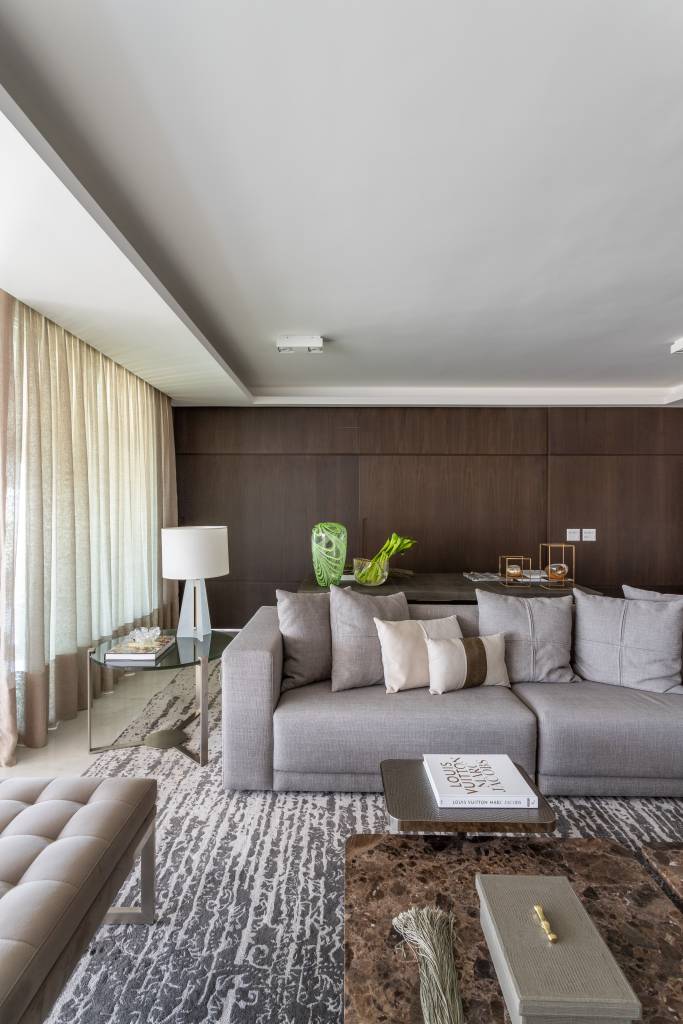Qual tamanho o tapete deve ter em cada cômodo? Projeto de Patricia Penna Arquitetura e Design. Na foto, sala, sofá cinza.