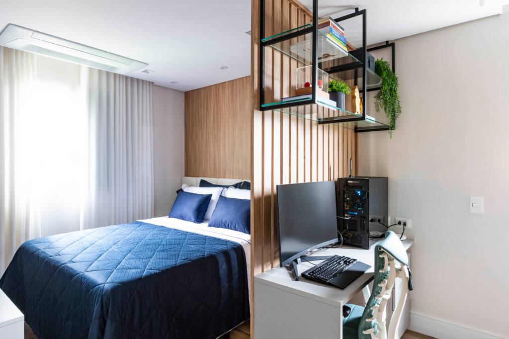 Reforma moderniza apartamento dos anos 1980 com integração e espaço para os pets da família. Projeto Daniela Funari. Na foto: quarto, dormitório, cama, painel de madeira, colcha azul, home office, prateleira de aço