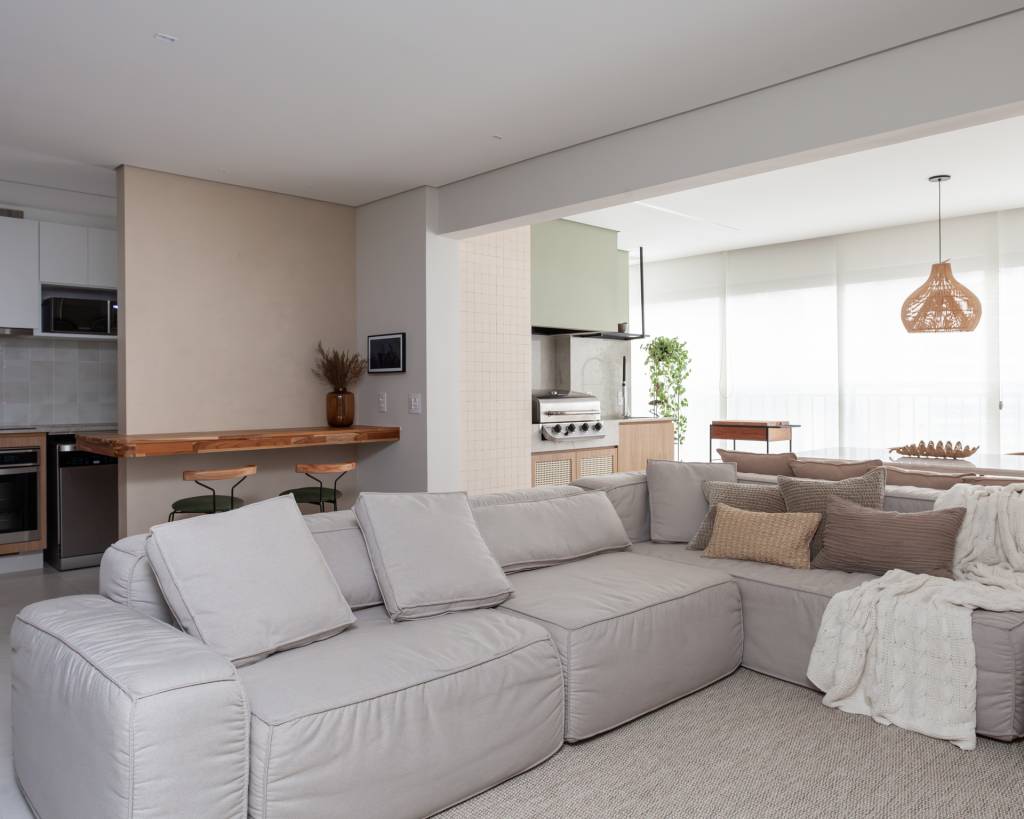Tons de verde suave permeiam gourmet, sala e quartos neste apê. Projeto de Studio Monfré. Na foto, sala, sofá branco, varanda integrada.