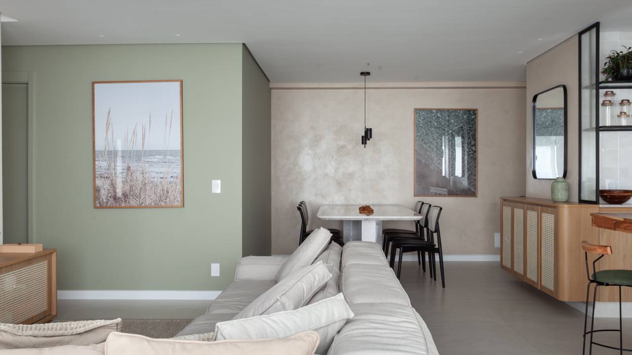 Tons de verde suave permeiam gourmet, sala e quartos neste apê. Projeto de Studio Monfré. Na foto, sala, sofá branco.
