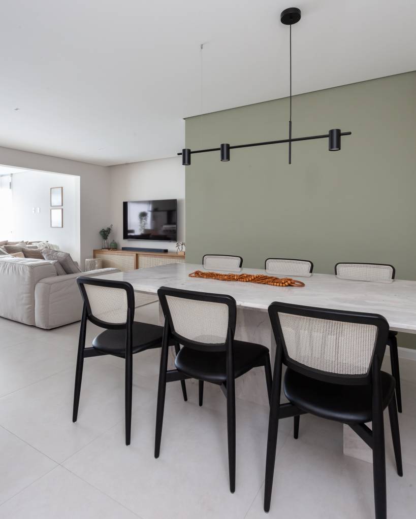 Tons de verde suave permeiam gourmet, sala e quartos neste apê. Projeto de Studio Monfré. Na foto, jantar, cadeira de madeira preta e palhinha.