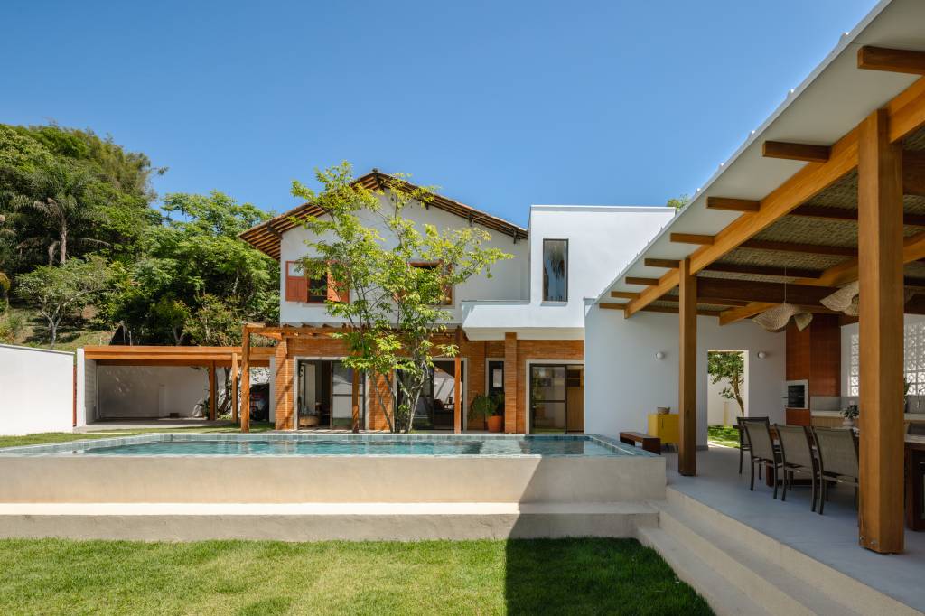 Casa com clima de praia em São José dos Campos. Projeto de escritório Sertão Arquitetos. Na foto, jardim de casa com piscina e área de churrasqueira.