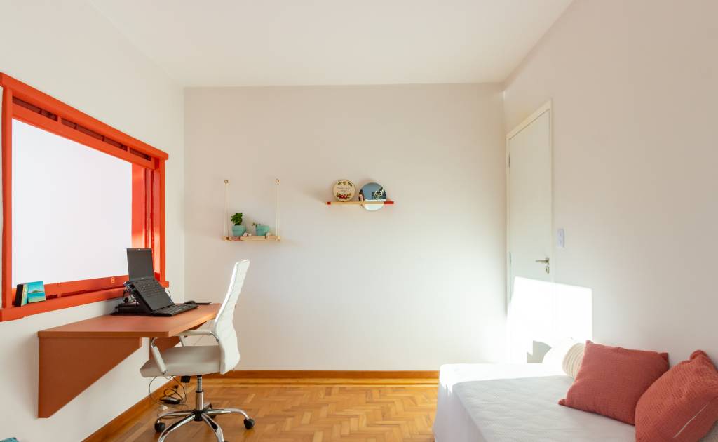 Casa com parede de tijolinhos e detalhes em cores primárias. Projeto de Sertão Arquitetos. Na foto, home office com mesa de trabalho.