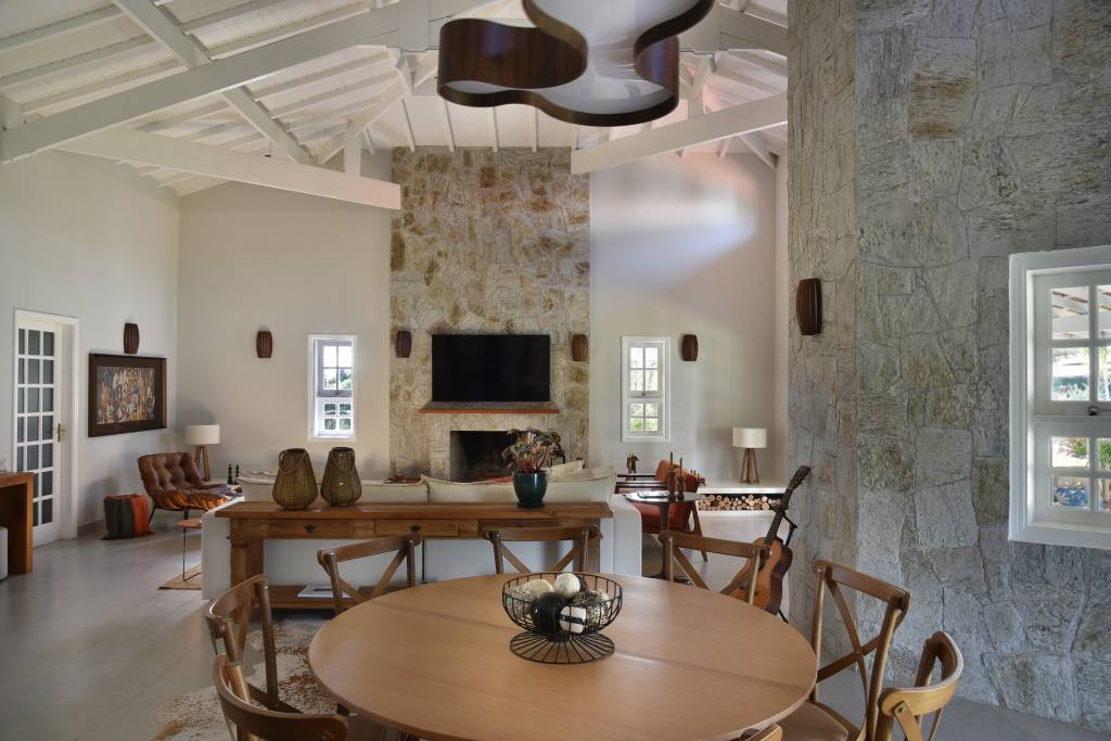 Casa de veraneio: 5 ideias para o décor. Projeto de Rosangela Pena. Na foto, sala com lareira e revestimento em pedra.