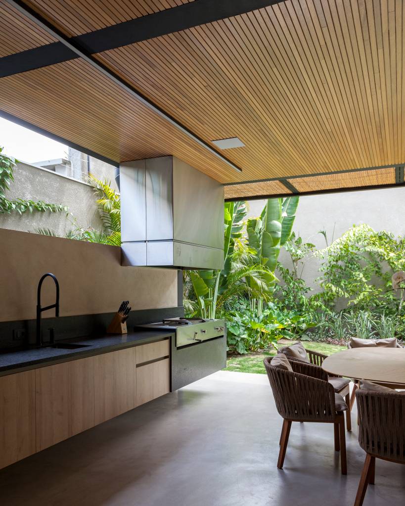 Casa em formato de “H” garante vista contínua do jardim. Projeto de Sandra Sayeg. Na foto, varanda com área gourmet.