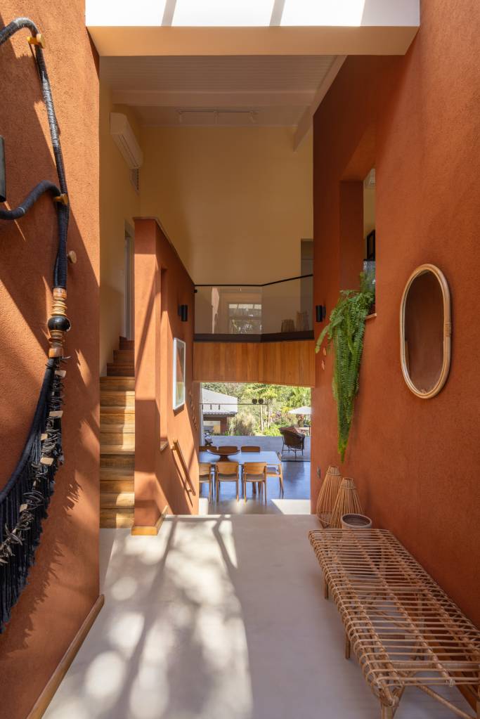 Casa nos arredores de São Paulo tem tons de terracota no interior e exterior. Projeto de Sertão Arquitetos. Na foto, hall de entrada com diversas peças de decoração.