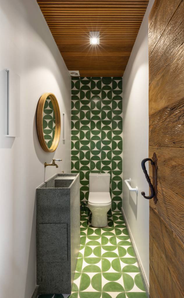 Casa nos arredores de São Paulo tem tons de terracota no interior e exterior. Projeto de Sertão Arquitetos. Na foto, lavabo com ladrilhos em verde e branco.