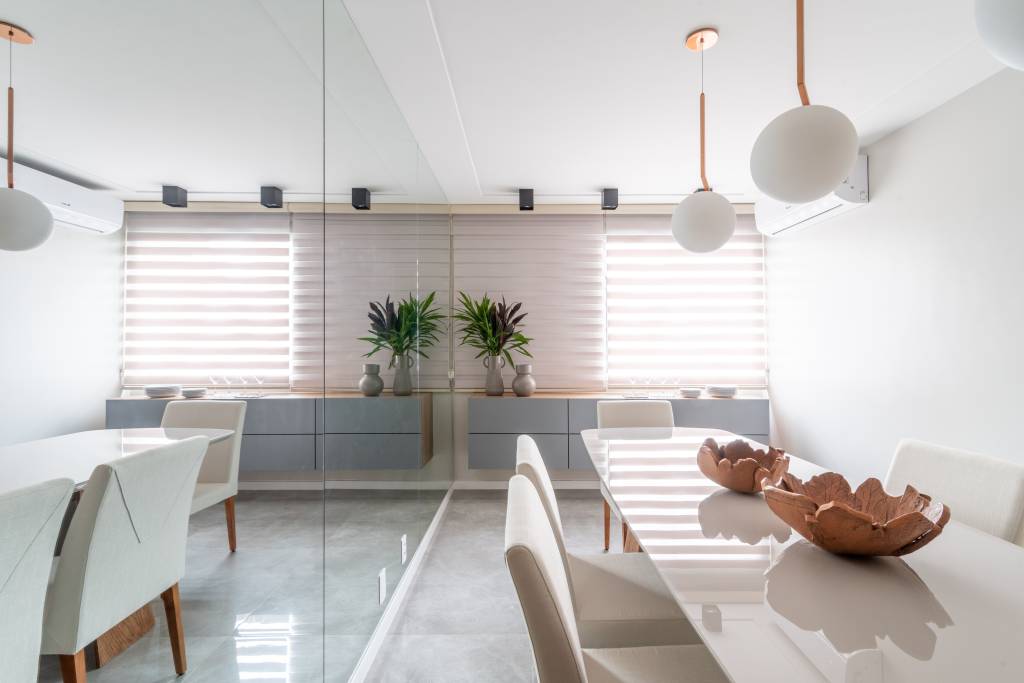 Como acertar na escolha do modelo de persianas e telas solares para cada ambiente. Projeto de Isabella Nalon. Na foto, sala de jantar com parede de espelho.