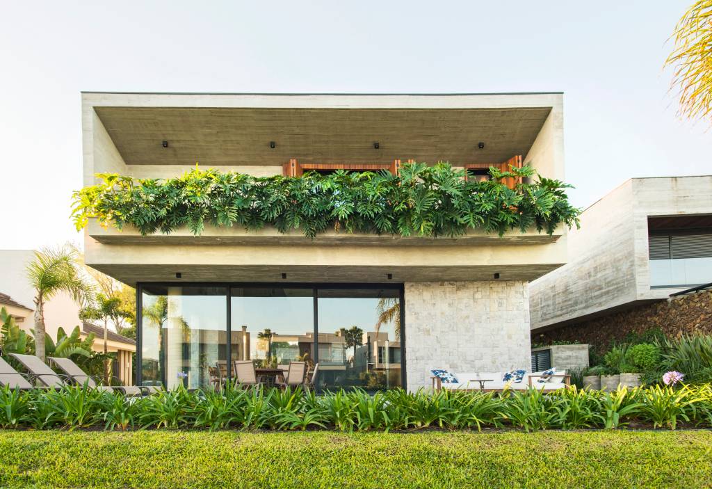 Casa de praia de 406 m² combina brutalismo, arte e sustentabilidade. Projeto de Mayresse Arquitetura. Na foto, área externa com piscina e jardim.