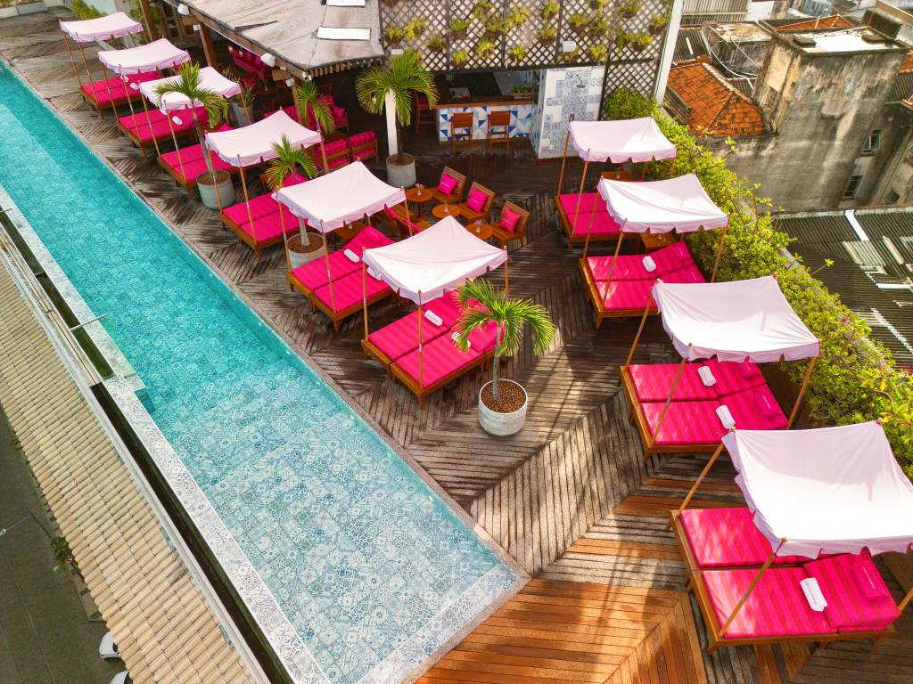 Rooftop de hotel parece ter saído do filme da Barbie. Na foto, rooftop de hotel com espreguiçadeiras rosas.