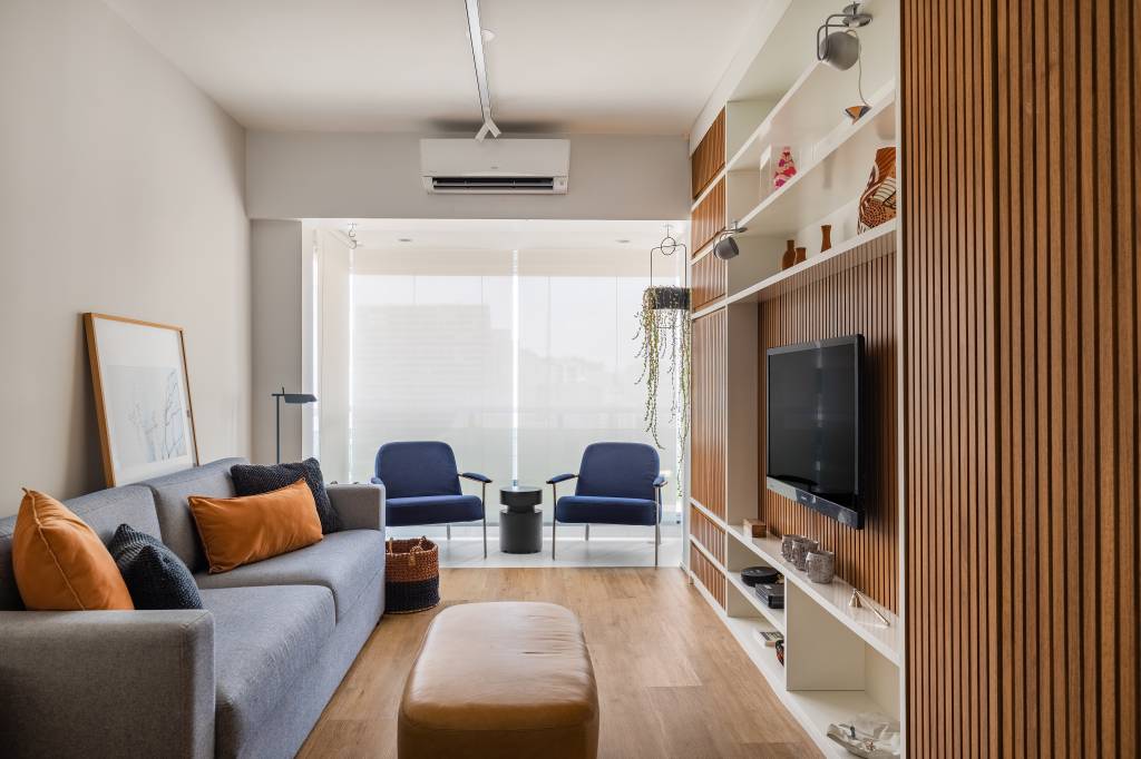 Apartamento compacto de 38 m² tem piso vinílico aquecido e canto alemão. Na foto, sala de estar, sofá cinza.