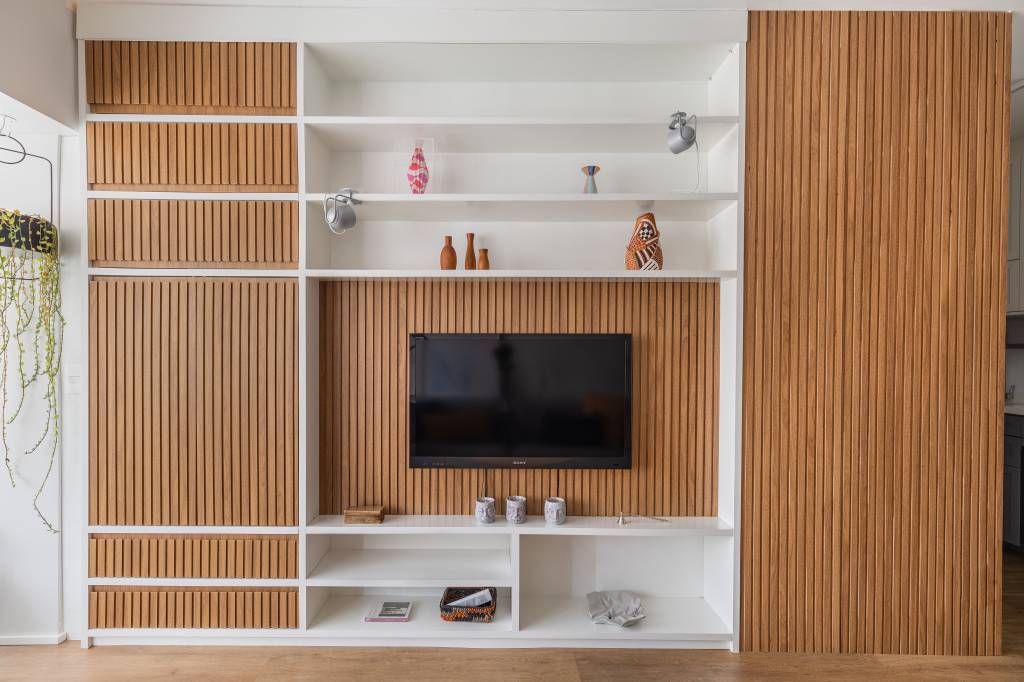 Apartamento compacto de 38 m² tem piso vinílico aquecido e canto alemão. Na foto, sala de estar, painel ripado.