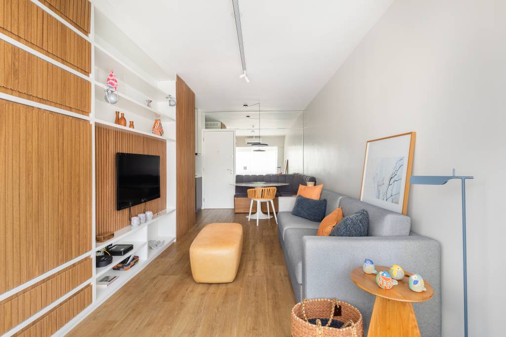 Apartamento compacto de 38 m² tem piso vinílico aquecido e canto alemão. Na foto, sala de estar, sofá cinza.