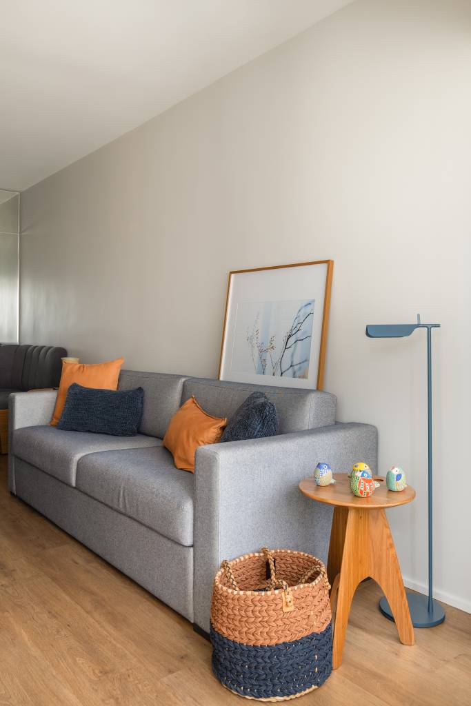 Apartamento compacto de 38 m² tem piso vinílico aquecido e canto alemão. Na foto, sala de estar, sofá cinza.