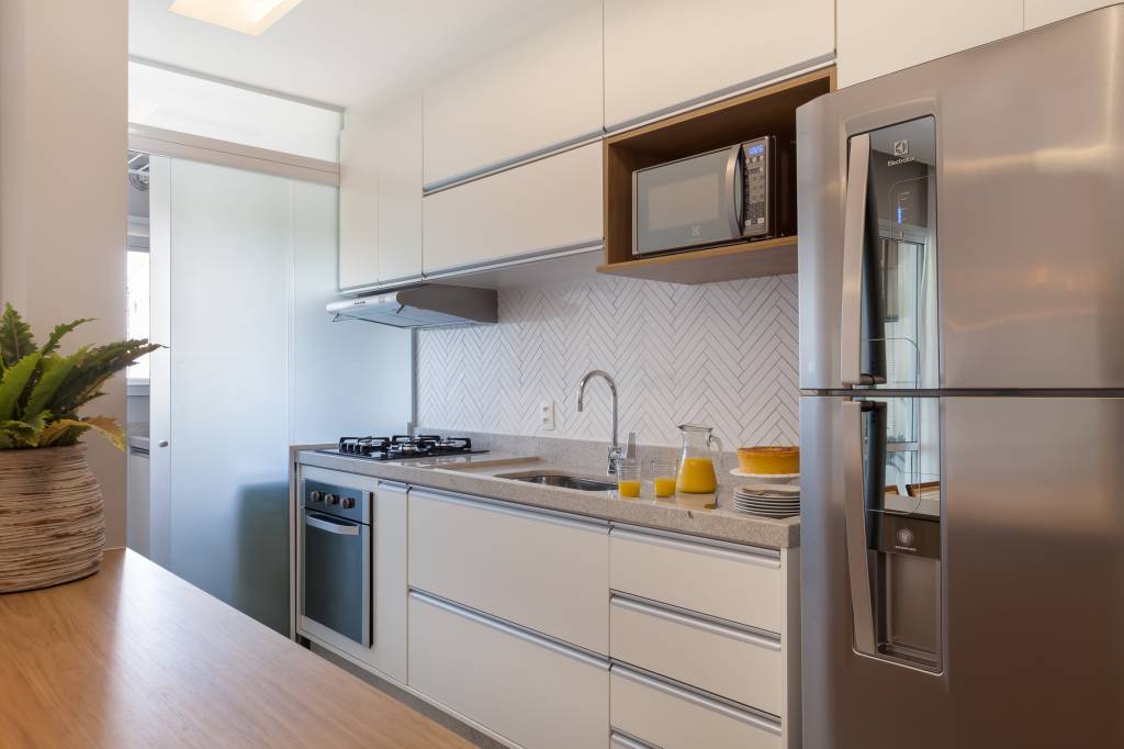 Varanda de apartamento tem serralheria preta com nichos e rede amarela. Projeto de RMV Interiores.