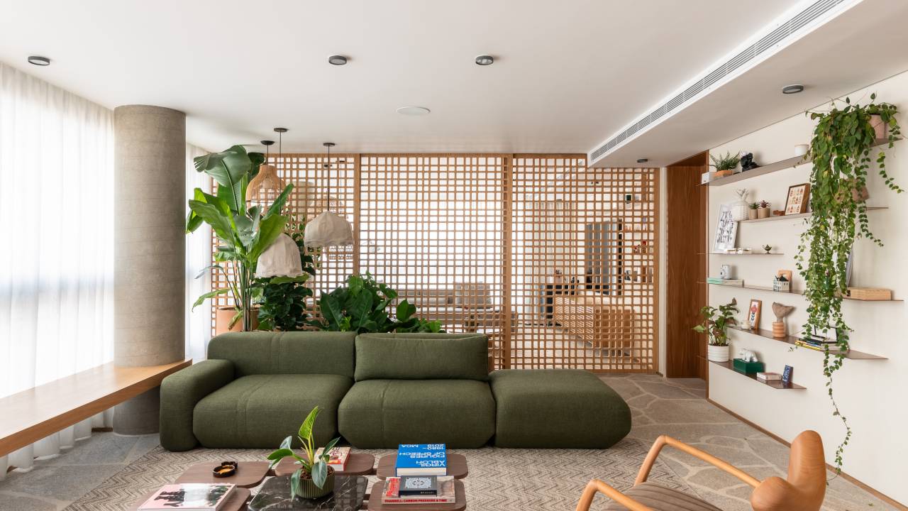 Apê de 333m² tem piso em pedra natural. Projeto de Labra Arquiteto. Na foto, área social com portas de muxarabi e sofá verde.