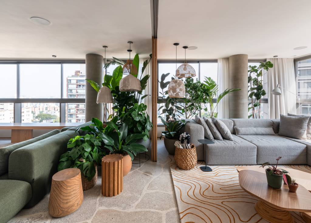 Apê de 333m² tem piso em pedra natural. Projeto de Labra Arquiteto. Na foto, área social com vasos de plantas.