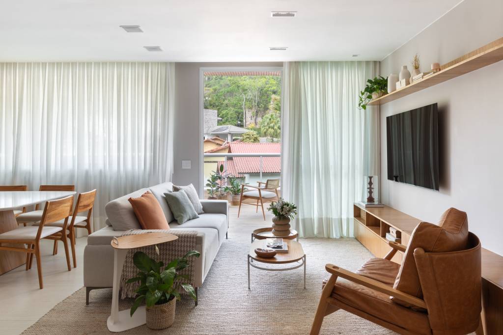 Apê tem estante tipo colmeia que abriga 15 nichos e cristaleira. Projeto de Ikeda Arquitetura. Na foto, sala com janela extensa.