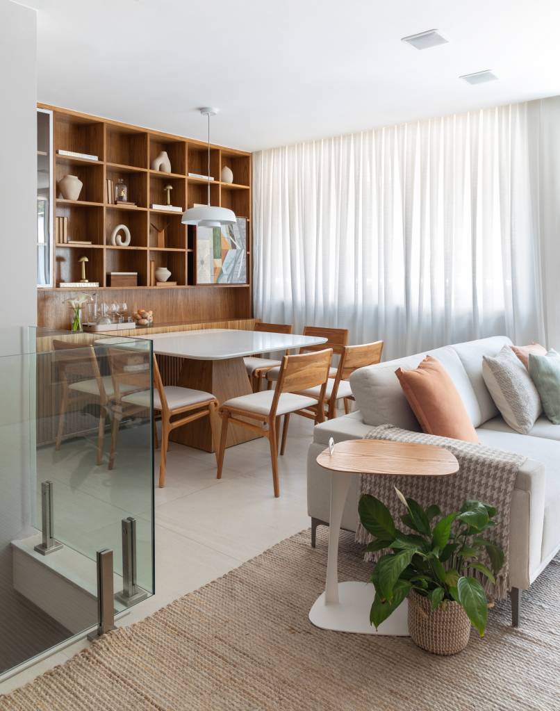 Apê tem estante tipo colmeia que abriga 15 nichos e cristaleira. Projeto de Ikeda Arquitetura. Na foto, mesa de jantar integrada com a sala de estar.