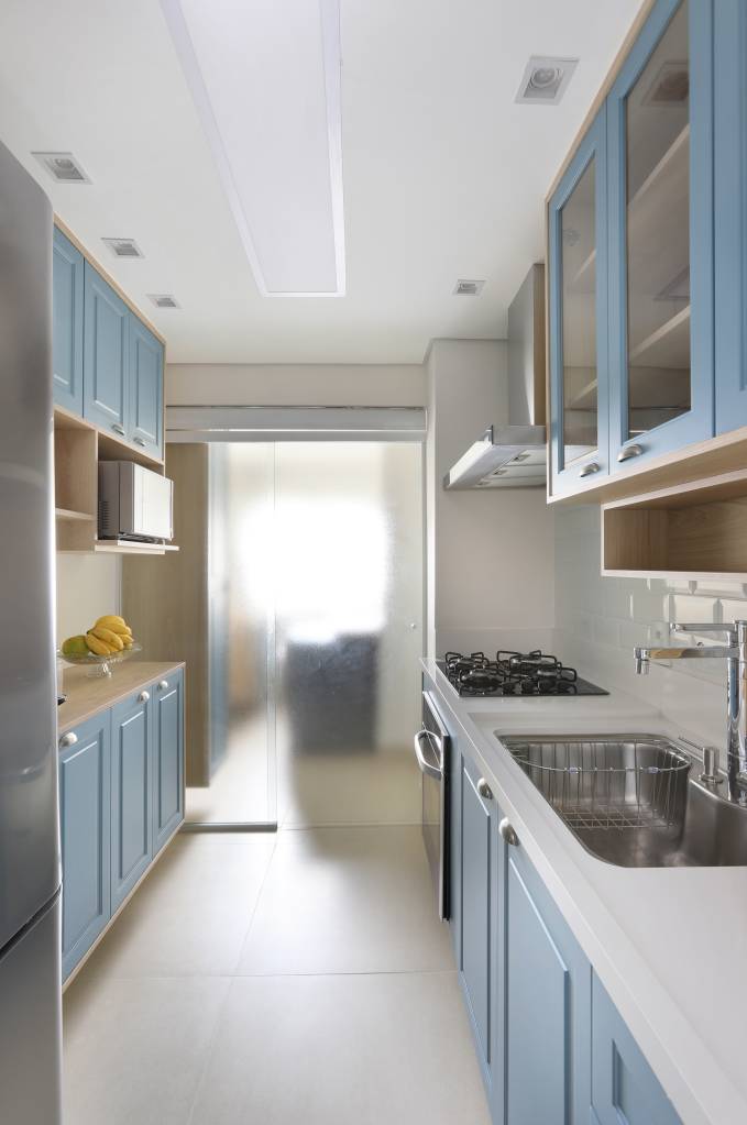 Armários em laca azul se destacam na cozinha deste apartamento. Projeto de RMV Interiores. Na foto, cozinha com armários em azul.