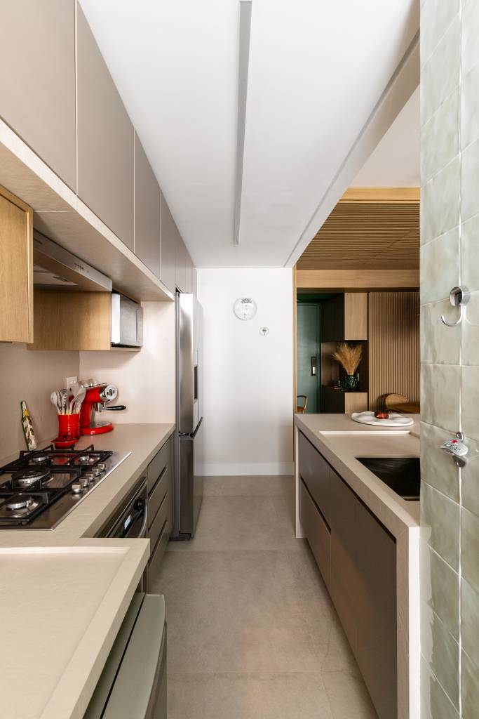 Arquiteta projeta o próprio apartamento e aposta em diferentes revestimentos. Projeto de Elisa Maretti. Na foto, cozinha com cooktop e itens em vermelho.