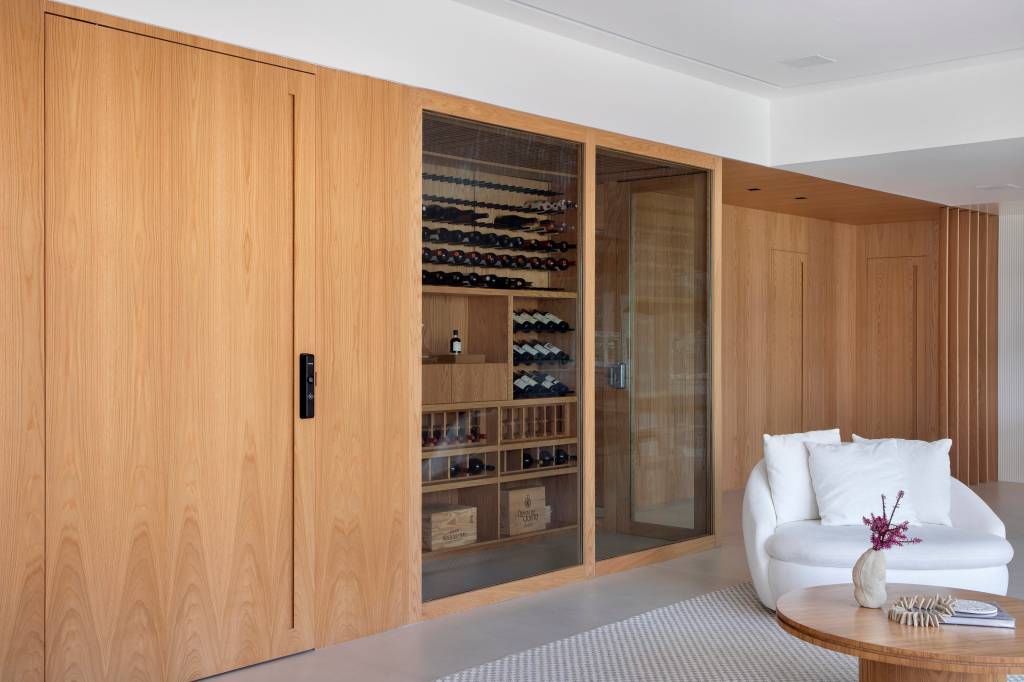 “Caixa” de madeira mimetizada esconde a porta de entrada deste apartamento e dá acesso à cozinha e ao lavabo. Projeto de Natalia Lemos Arquitetura.