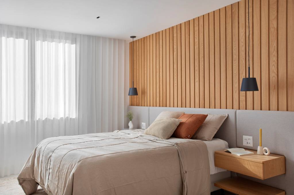“Caixa” de madeira mimetizada esconde a porta de entrada deste apartamento e dá acesso à cozinha e ao lavabo. Projeto de Natalia Lemos Arquitetura.