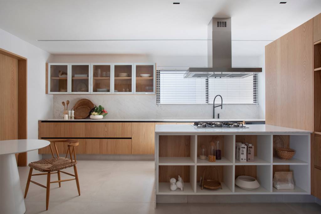 “Caixa” de madeira mimetizada esconde a porta de entrada deste apartamento e dá acesso à cozinha e ao lavabo. Projeto de Natalia Lemos Arquitetura.