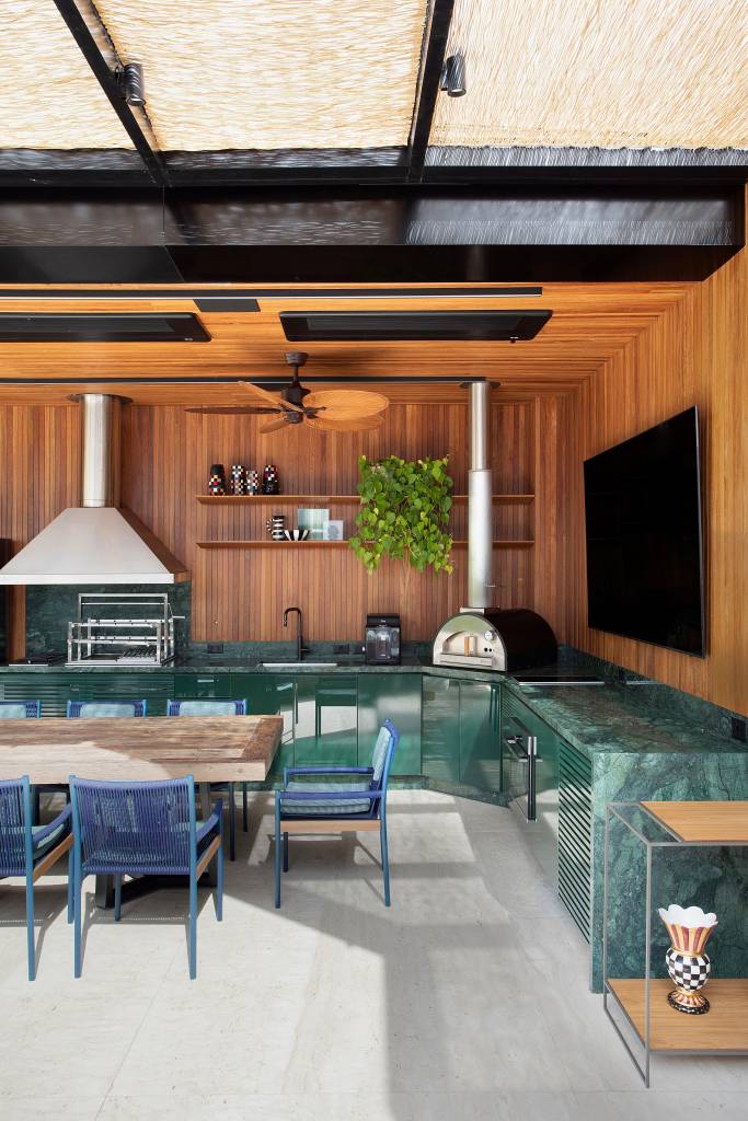 Jardineiras em mármore com plantas altas garantem privacidade neste apê. Projeto de Bianca da Hora. Na foto, espaço gourmet com mesa e espaço de trabalho.