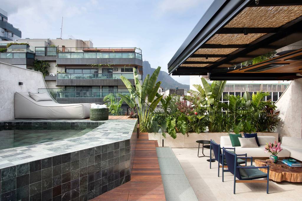 Jardineiras em mármore com plantas altas garantem privacidade neste apê