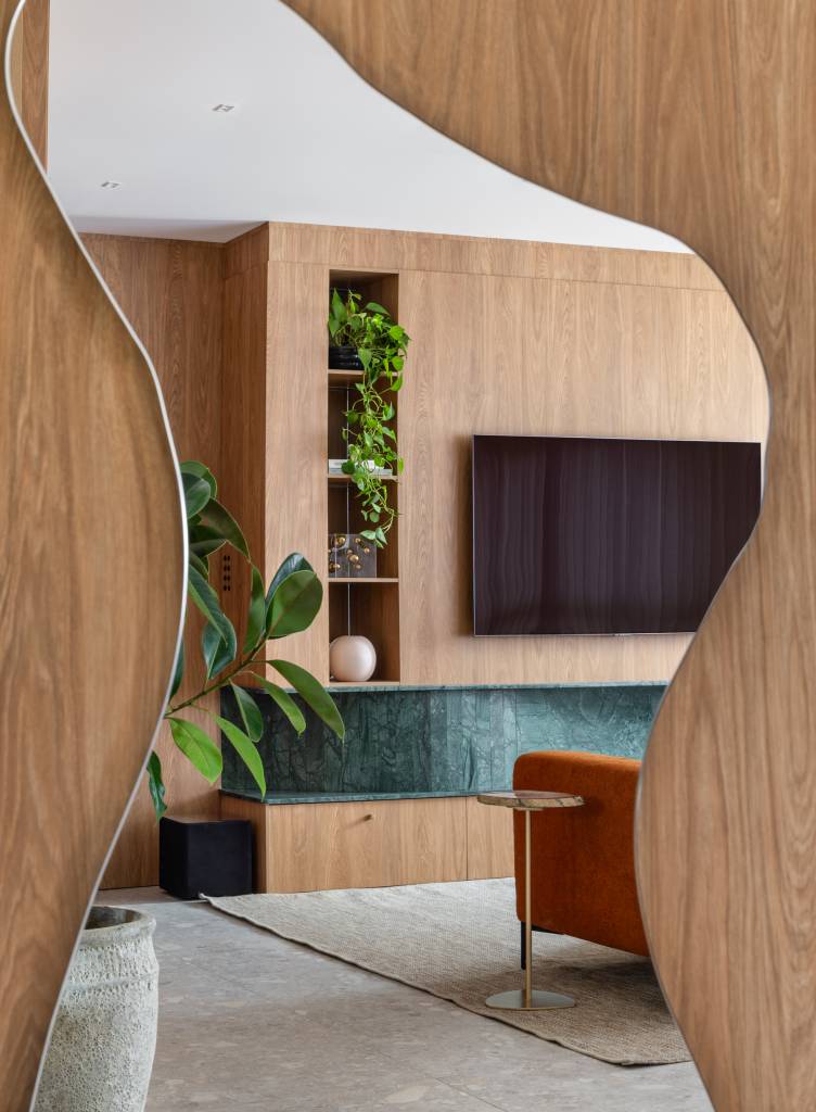 Lareira em mármore verde se destaca em apartamento de 170 m². Projeto de Natan Hostins Design. Na foto, espelho com forma orgânica.