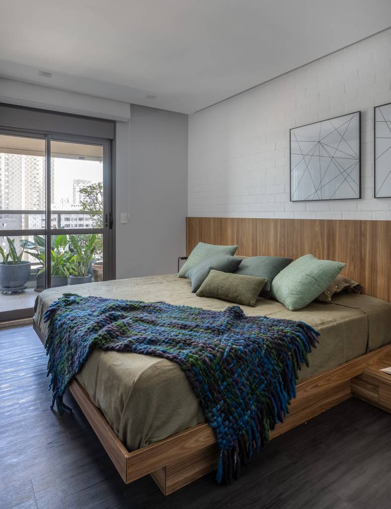 Apartamento descolado tem jardim vertical exuberante com samambaias e cozinha azul. Projeto de Flávia Campos.