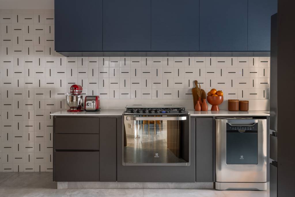 Apartamento descolado tem jardim vertical exuberante com samambaias e cozinha azul. Projeto de Flávia Campos.