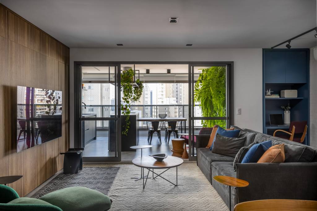 Apartamento descolado tem jardim vertical exuberante com samambaias e cozinha azul. Projeto de Flávia Campos.