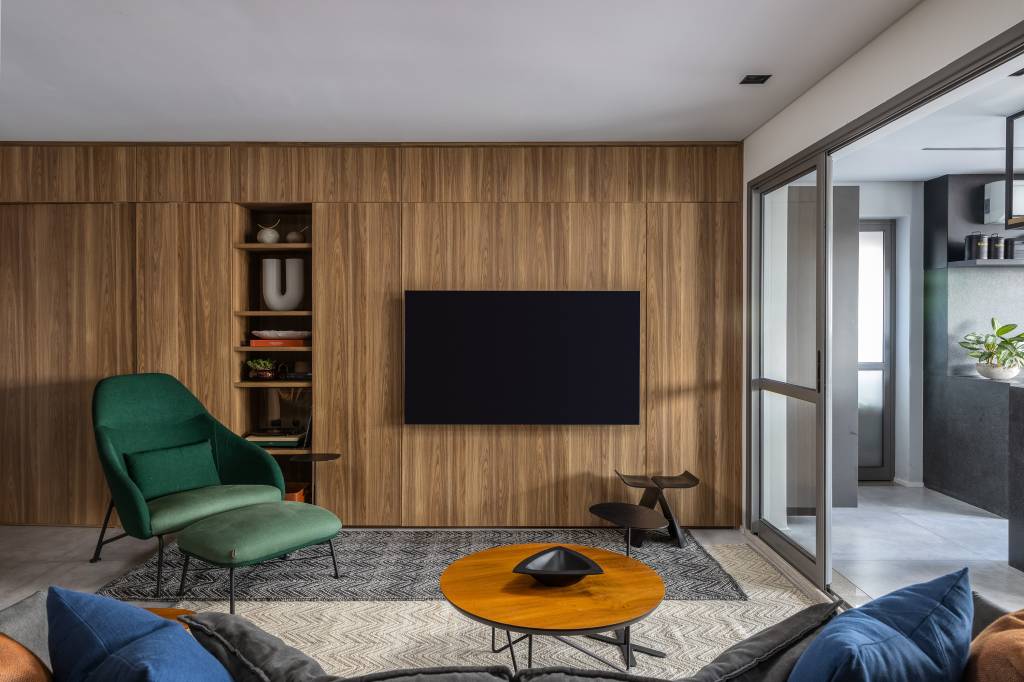 Apartamento descolado tem jardim vertical exuberante com samambaias e cozinha azul. Projeto de Flávia Campos.