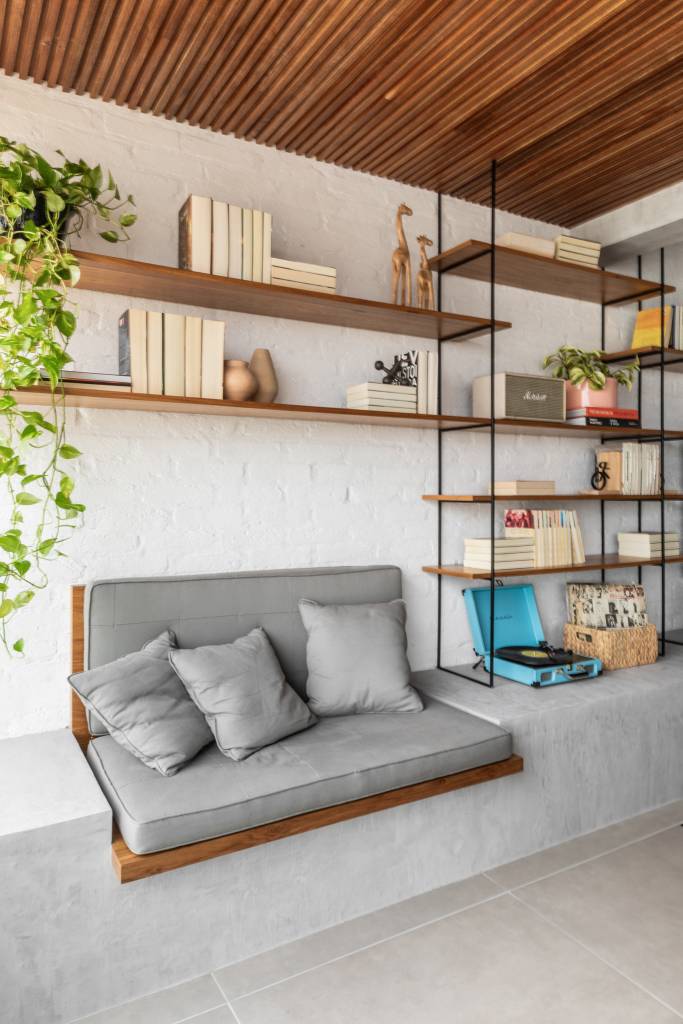 Apartamento integrado tem banco de concreto com futon na varanda. Projeto de Conectarq.