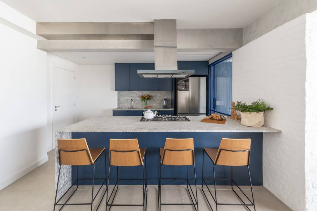 Apartamento integrado tem banco de concreto com futon na varanda. Projeto de Conectarq.