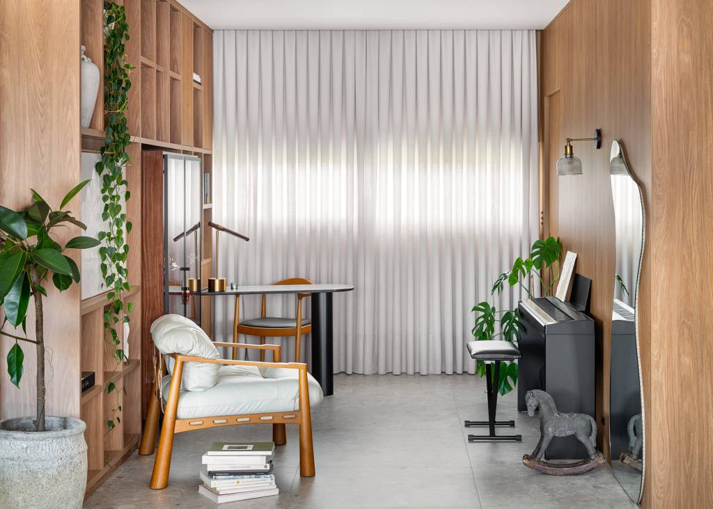 Lareira em mármore verde e toques musicais se destacam em apartamento de 170 m². Projeto de Natan Hostings Design.