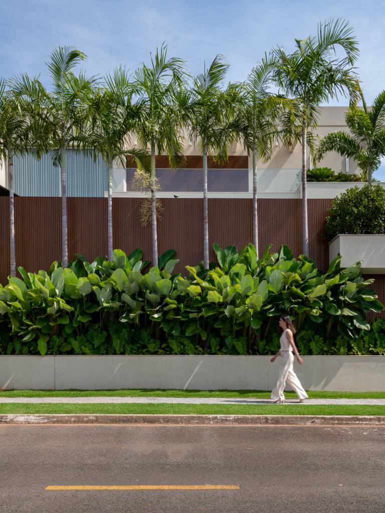 Palmeiras abraçam fachada e piscina nesta casa com paisagismo tropical. Paisagismo de Flávia D’urso.