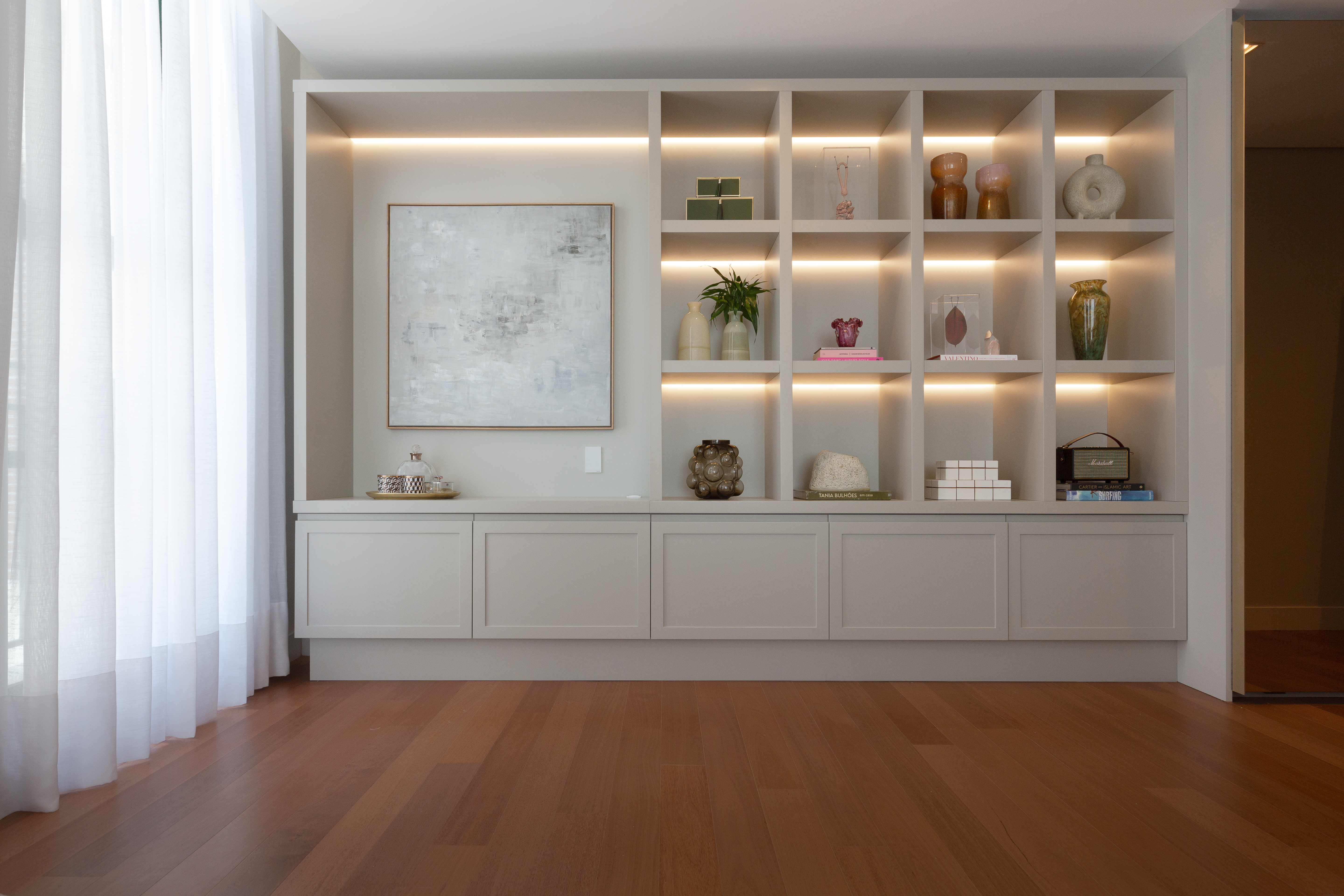 Apartamento amplo tem estante sob medida com nichos para vasos e livros. Projeto de Sabrina Salles.